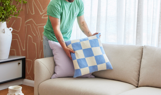 Man placing check cushion on couch