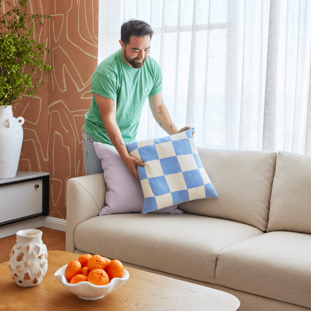 Man placing cushion on to couch