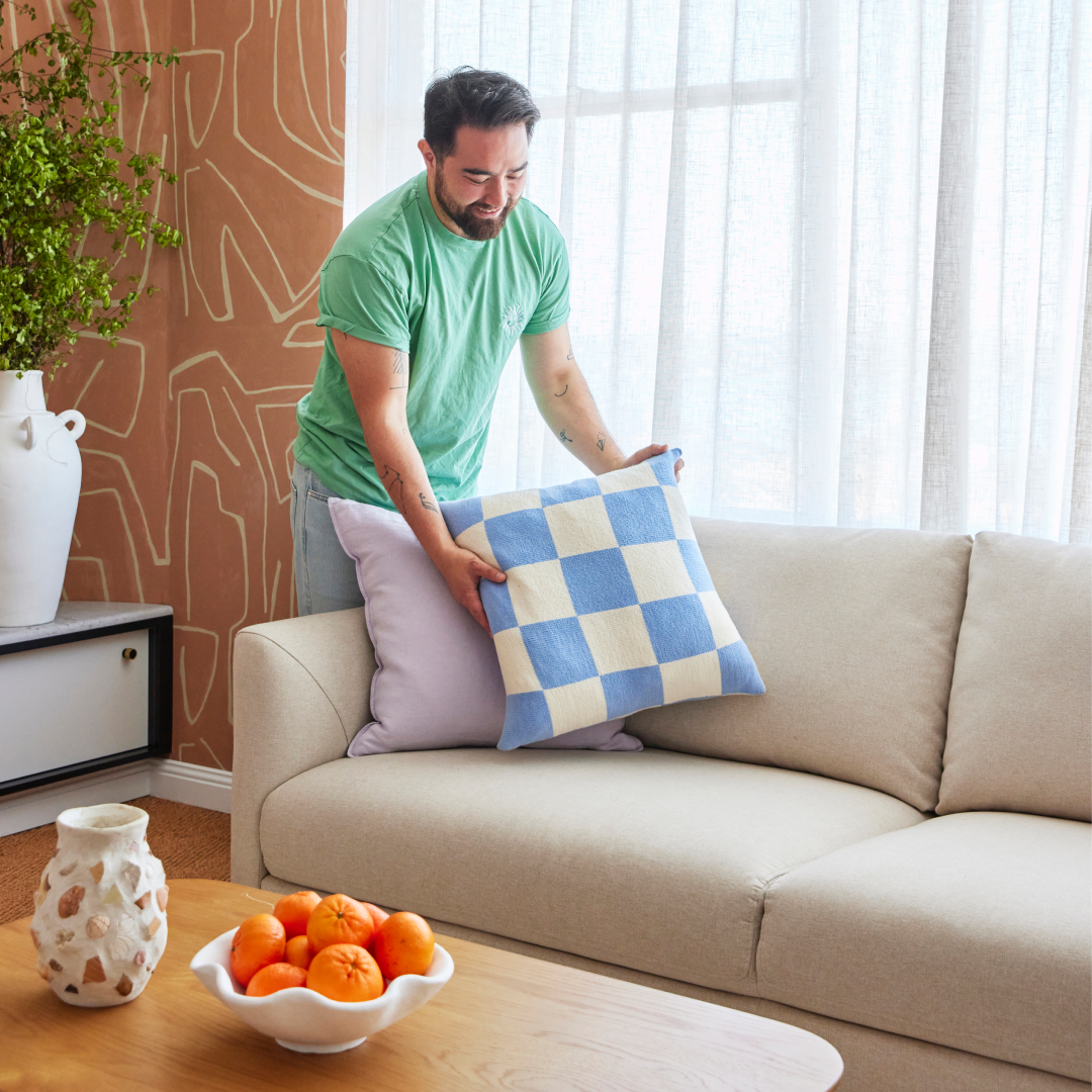 Man placing check cushion on couch