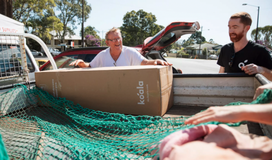 Two men standing over ute with Koala mattress box in tray