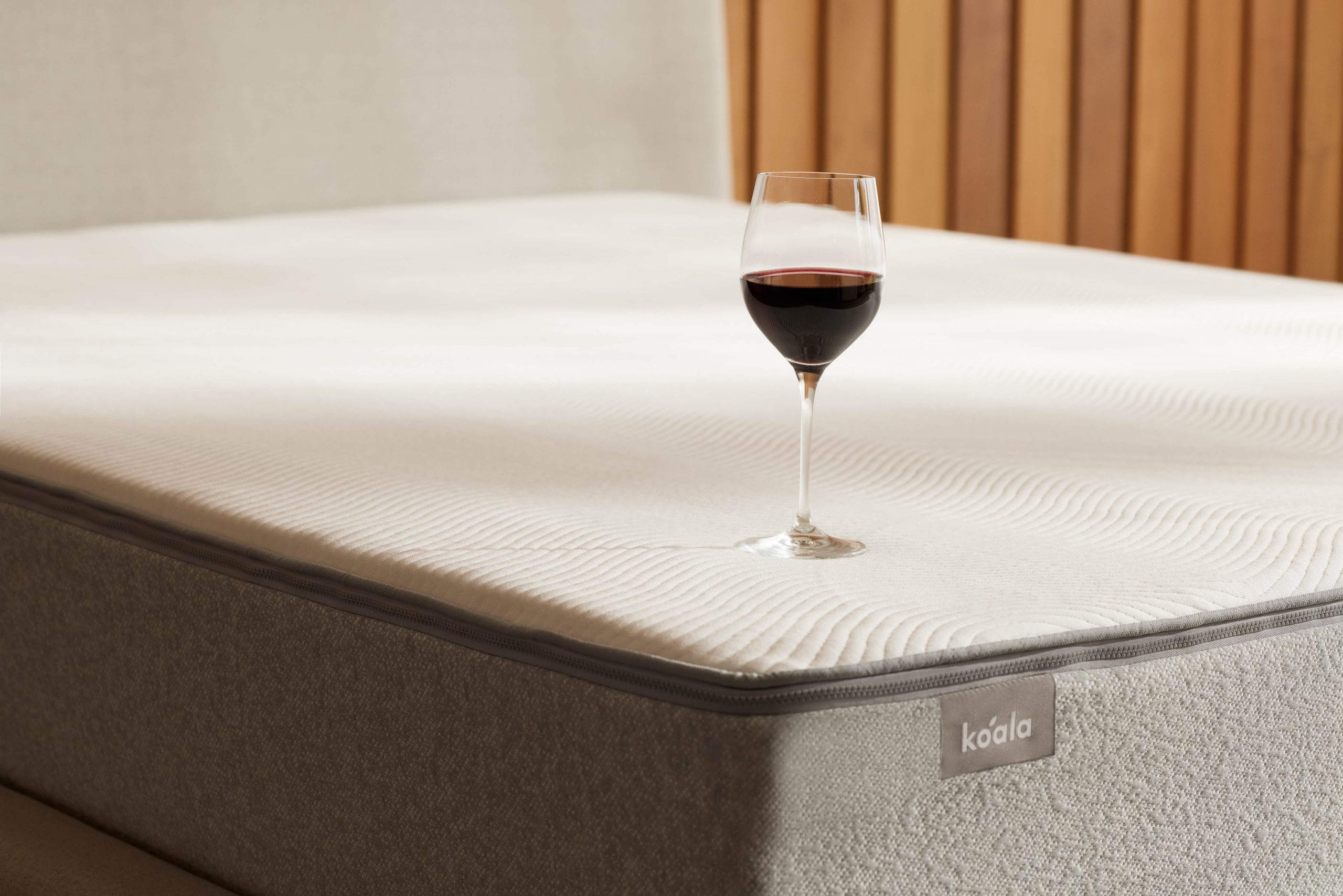 A clean mattress with a glass of red wine balanced on it. Once it spills you’ll need to know how to clean a mattress. 