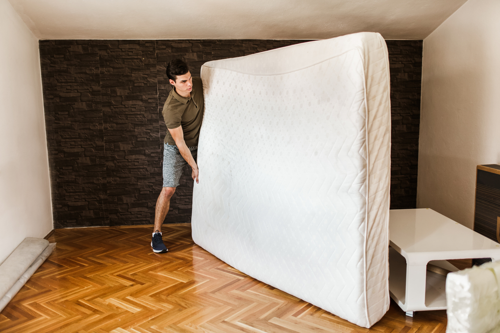 Man removing an old mattress from his apartment to make room for his new Koala mattress