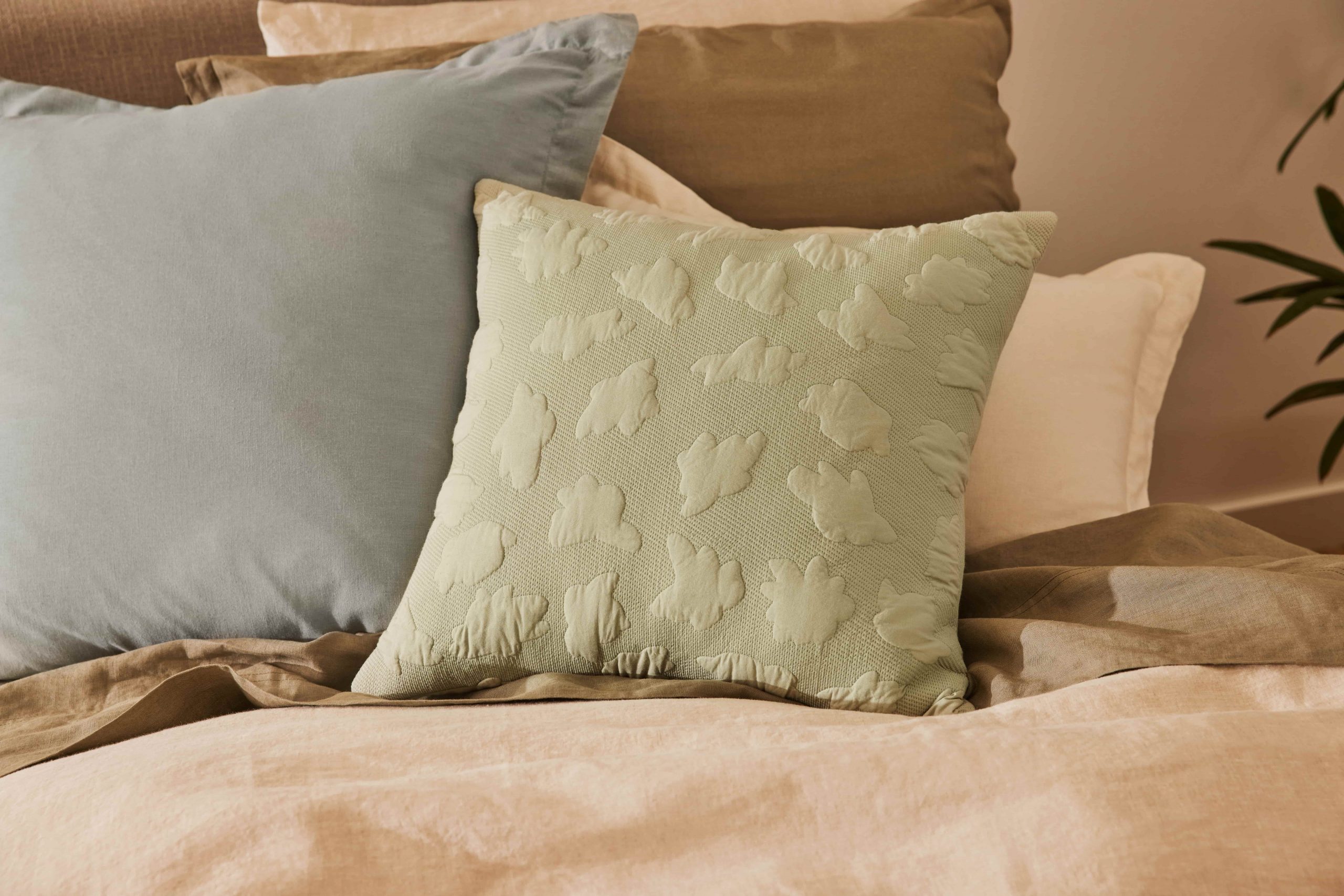 A light green cushion with cloud patterns in front of a steel blue cushion