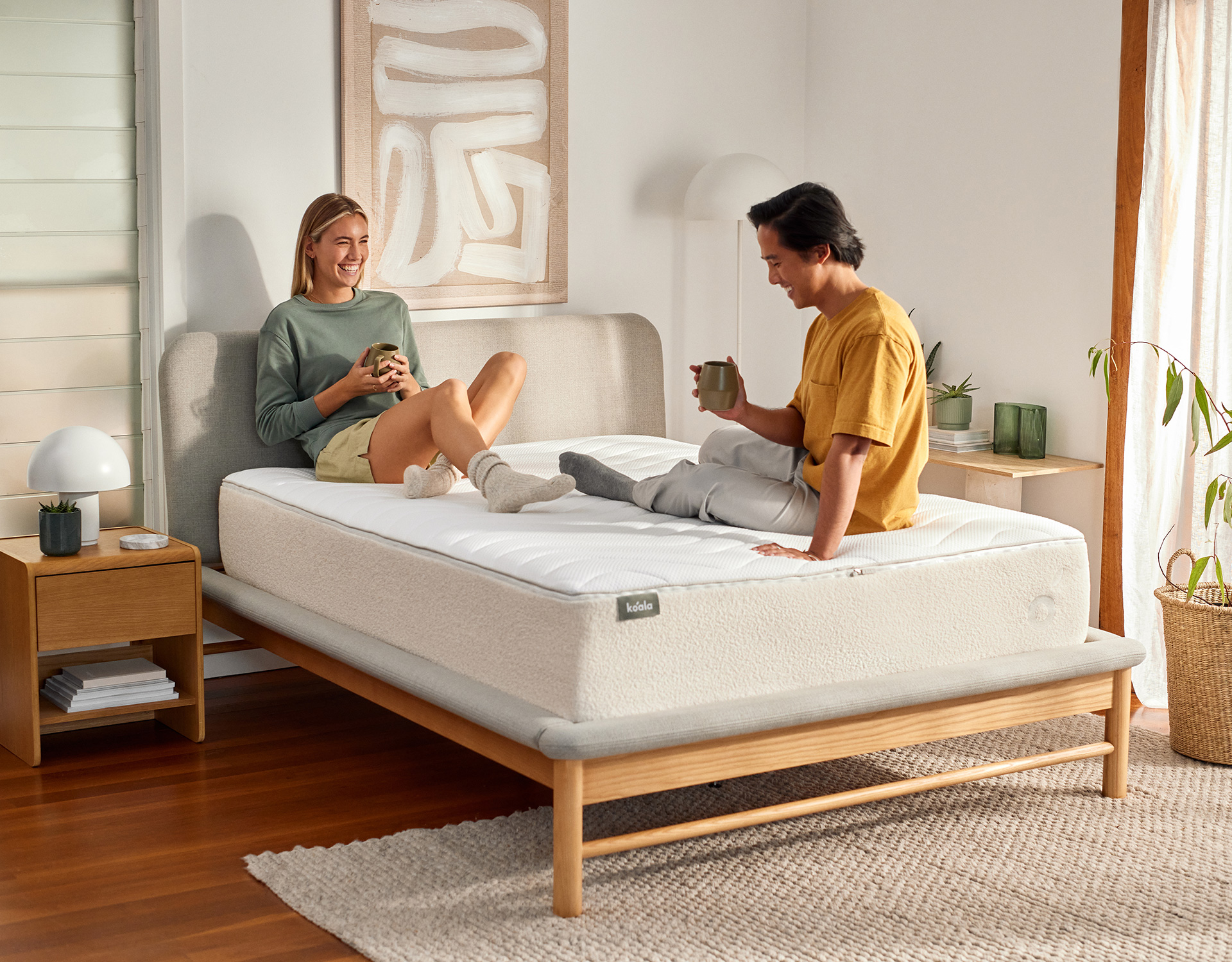 Smiling couple on a springless Koala mattress discovering that foam mattresses are just as good as pocket spring mattresses