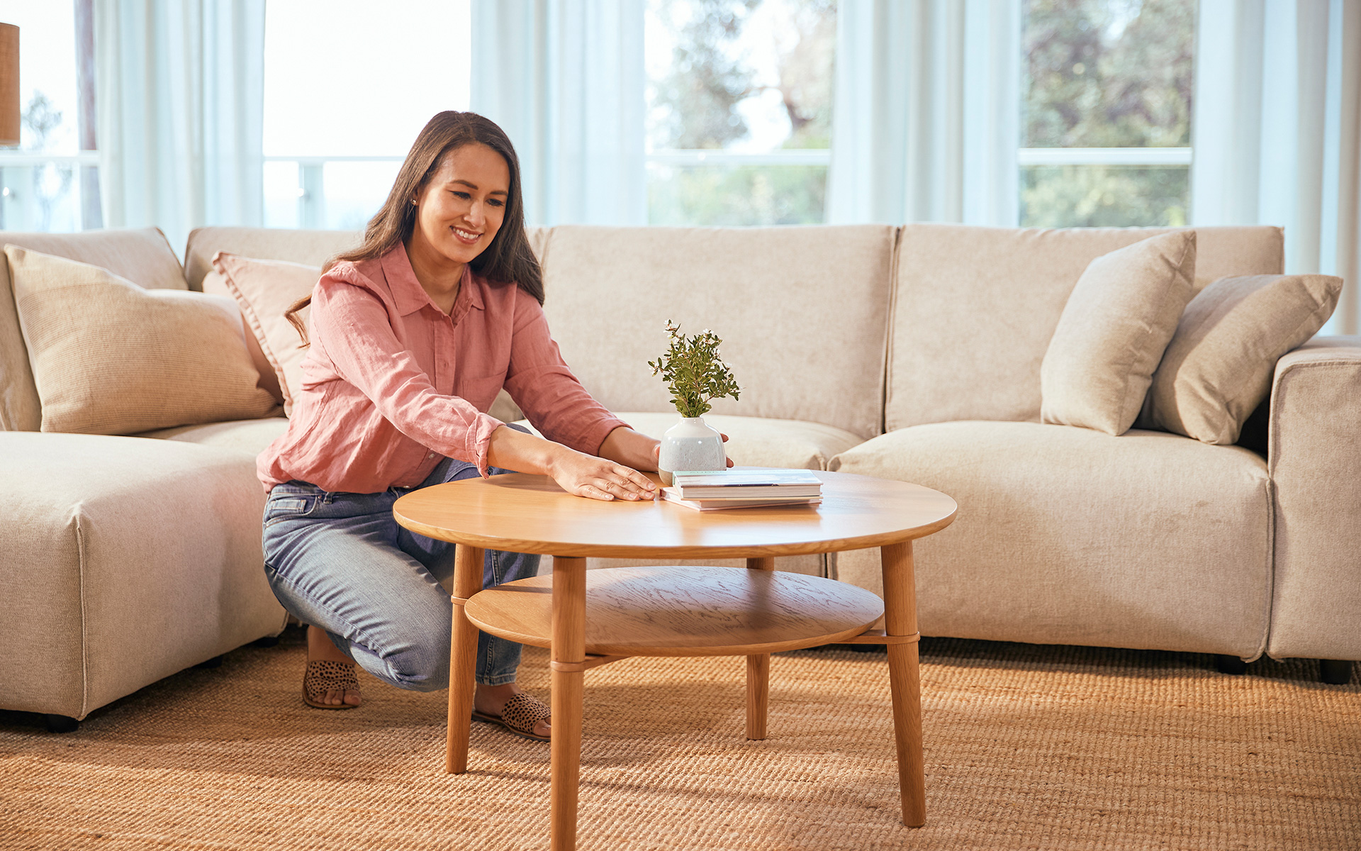 A woman smiles as she arranges a book and vase on her Scandi coffee table from Koala