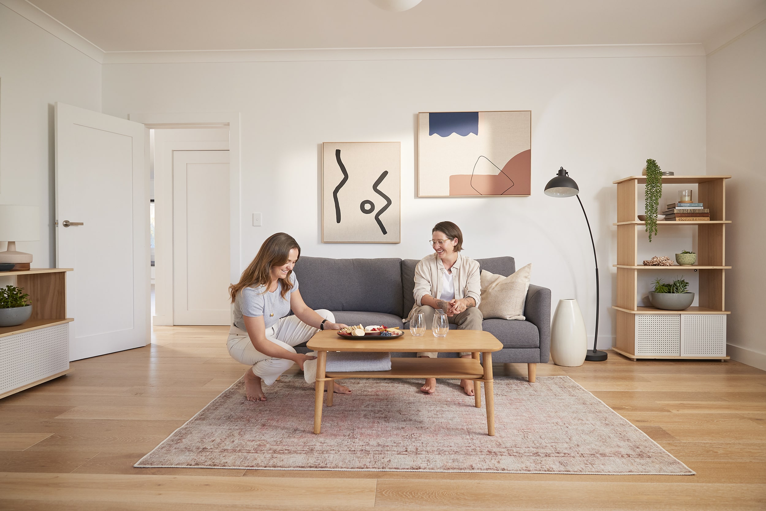 Two women settle down to enjoy a cheese platter from their beautiful Koala wood coffee table