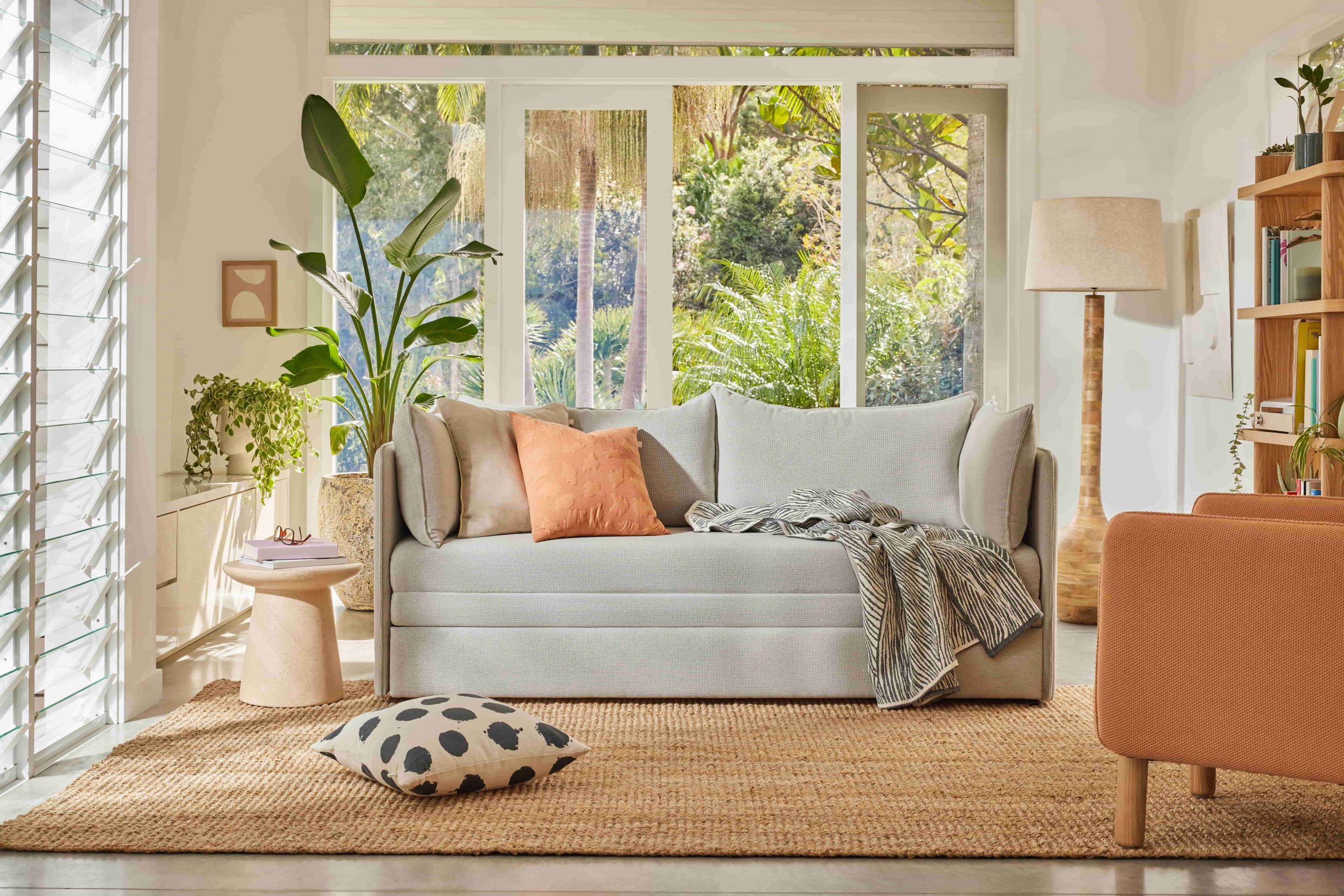Can I was pillows? Light grey sofa bed decorated with homewares in a sunlit room