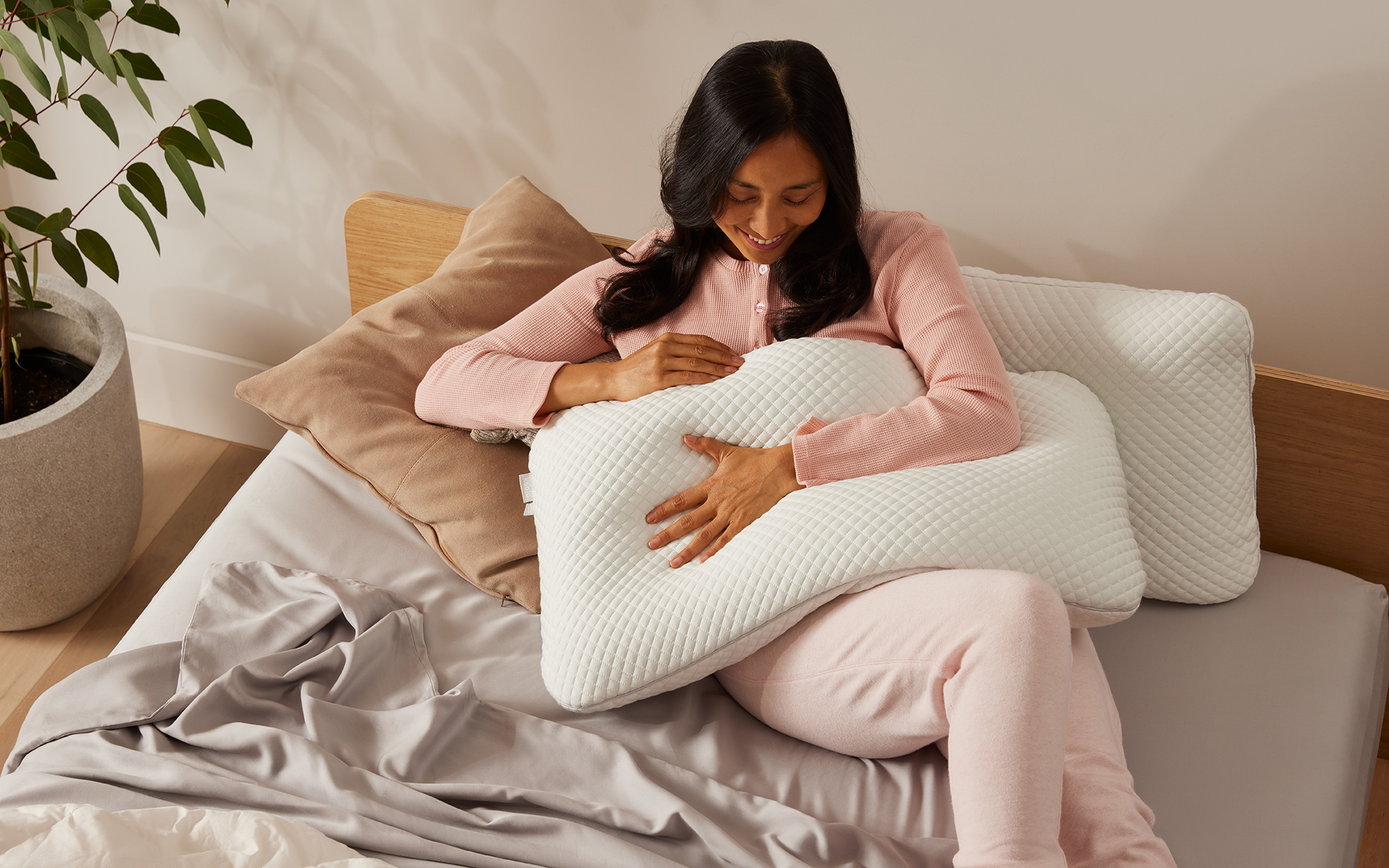 A woman snuggles up in bed after finding the best pillows Australia has to offer