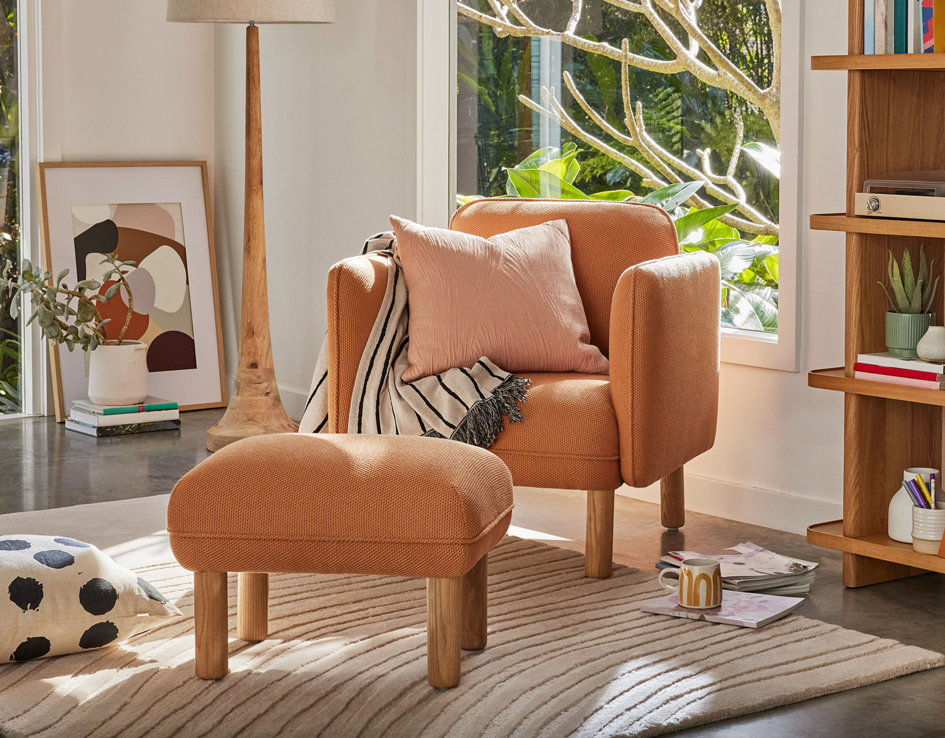 A Koala armchair and ottoman in a bright living room with rug, cushions and accessories