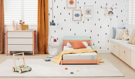 A large, colourful child’s bedroom filled with kids bedroom furniture such as a low bed, chest of drawers and a large rug