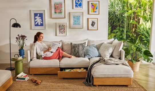 A woman relaxes on a Koala sofa with chaise as she reads a book in a bright and clean lounge room