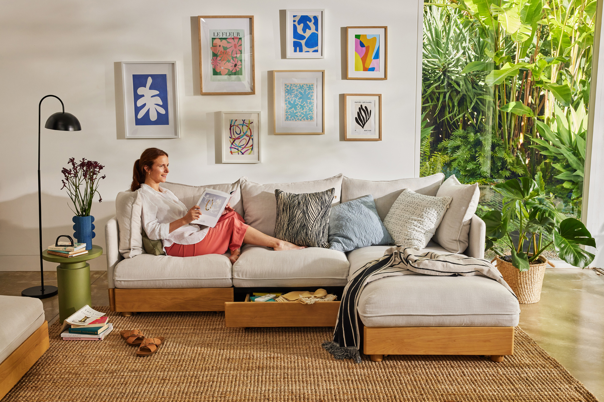 A woman relaxes on a Koala sofa with chaise as she reads a book in a bright and clean lounge room