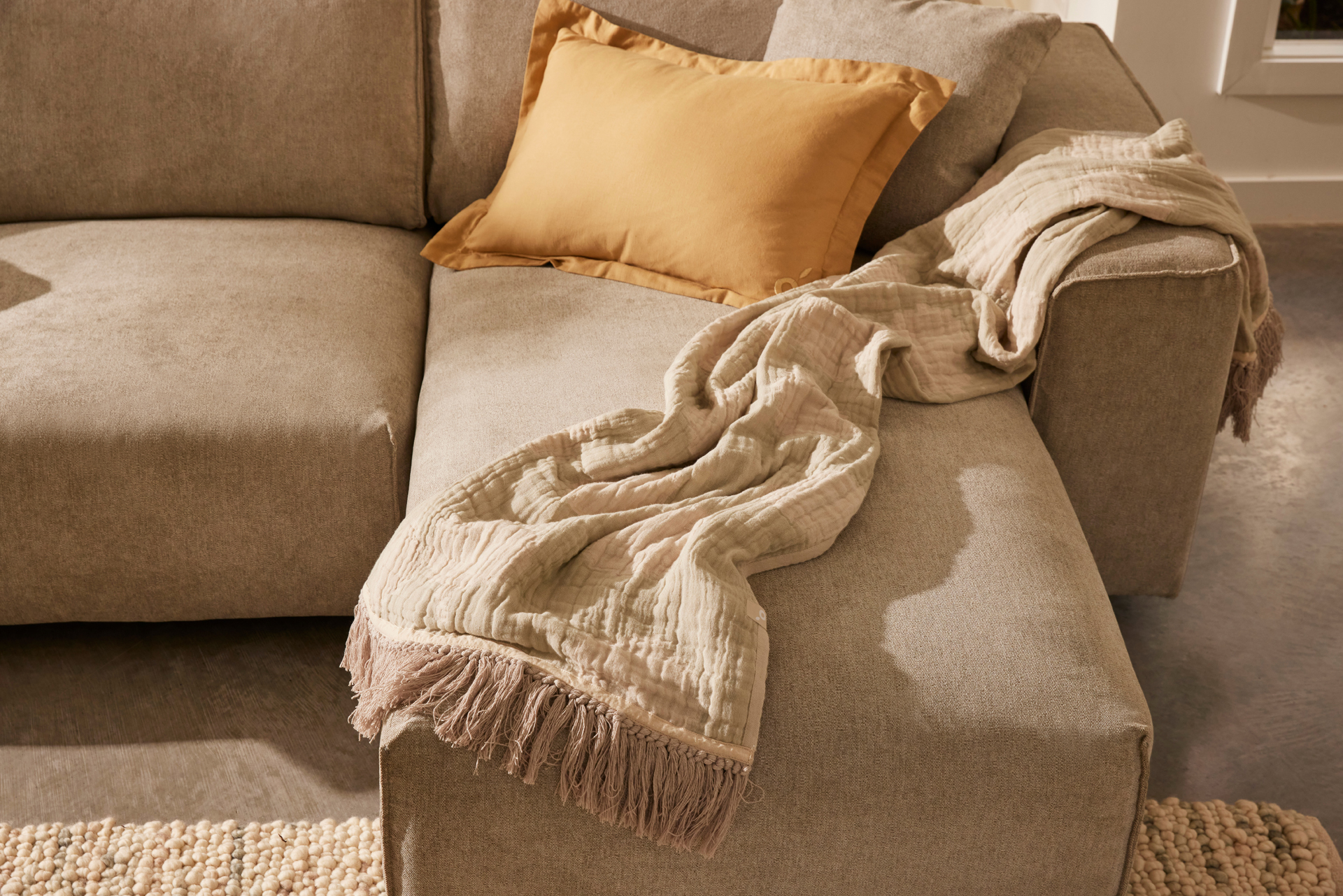 A textured throw casually draped on a couch with cushions