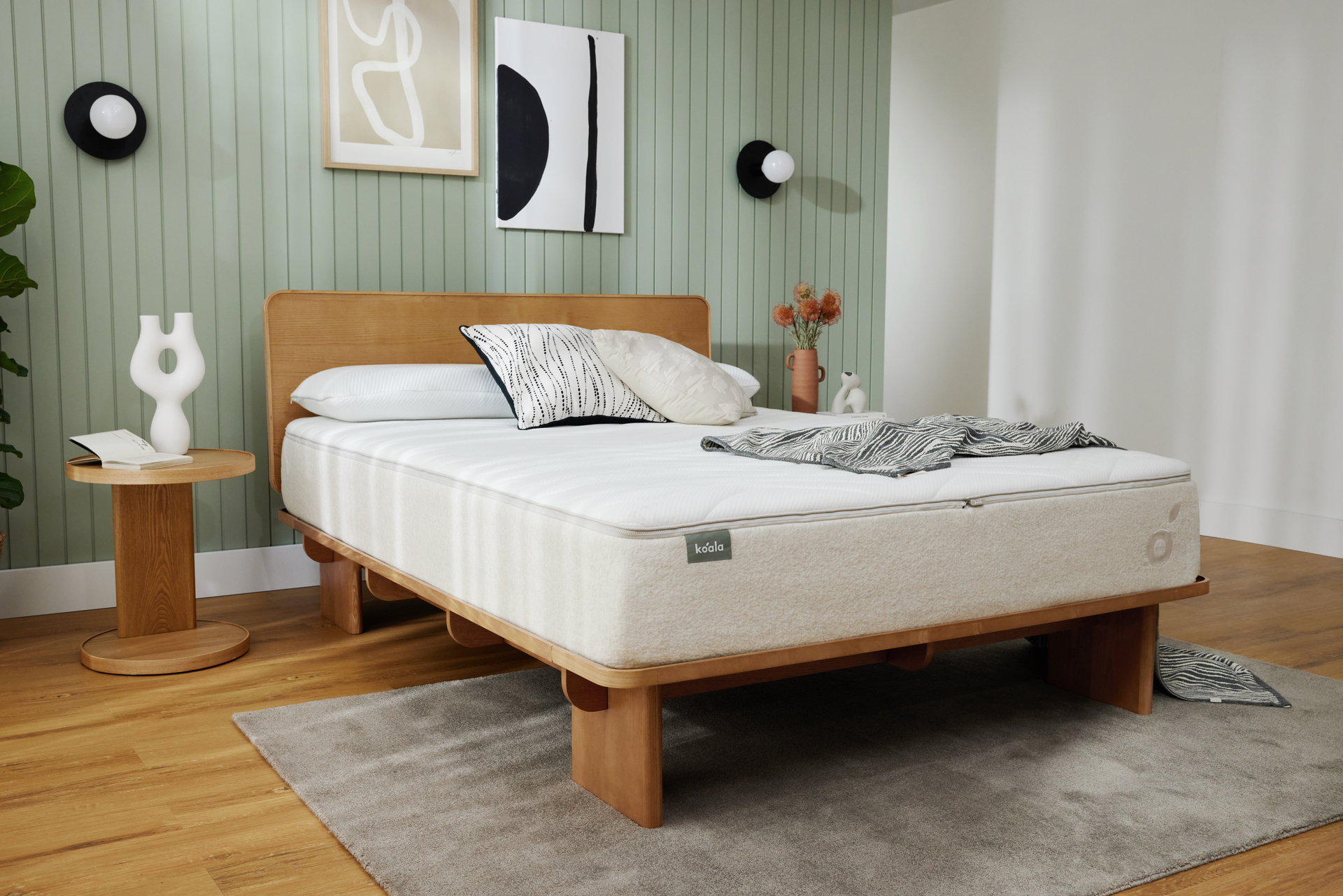 A Koala bed base and mattress in a large bedroom with green feature wall and timber flooring