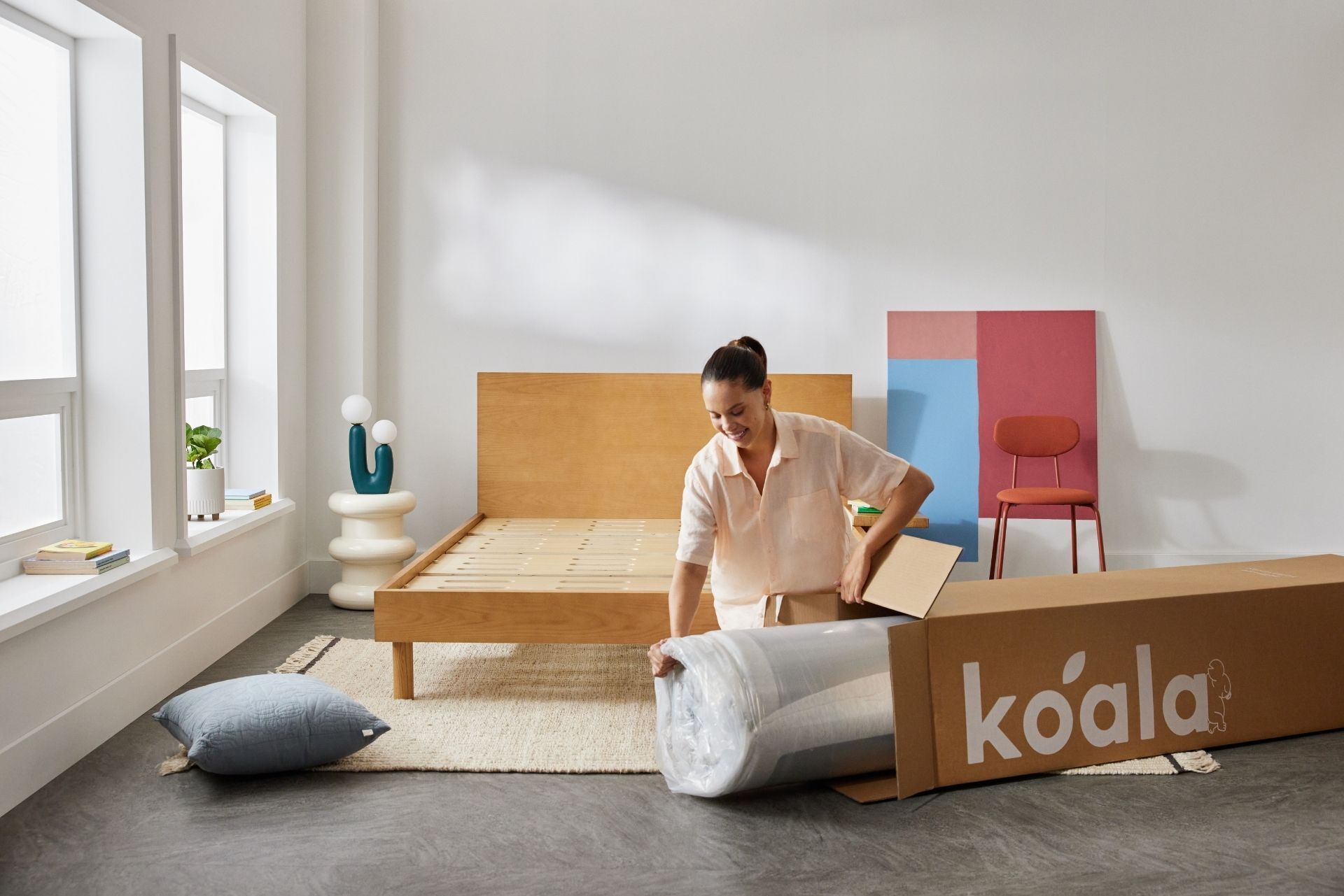 A young woman unpacks her new Koala mattress in a bright and airy bedroom